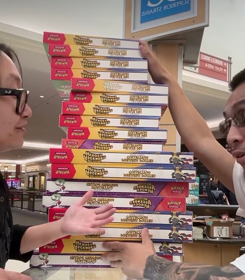Two people stacking pizza boxes with red and yellow labels in a retail store environment