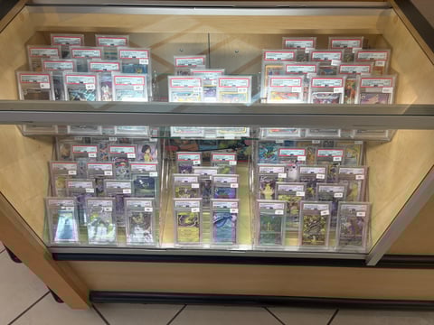 Display case with multiple shelves containing graded trading cards in protective cases